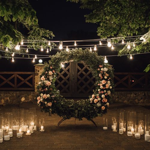 beautiful-photozone-with-big-wreath-decorated-with-greenery-roses-centerpiece-candles-sides-garland-hanged-trees